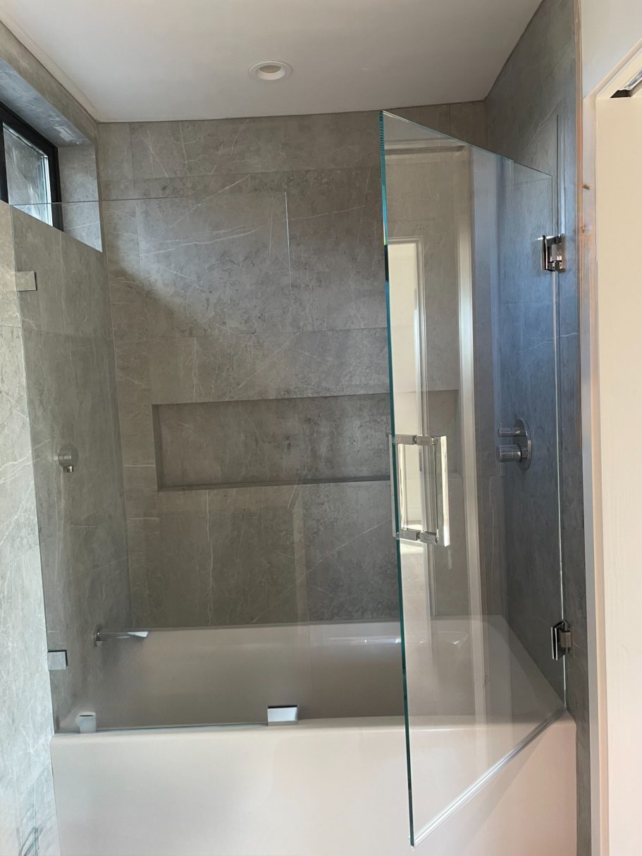 Frameless Custom Designed Bath Tub Enclosure Modern shower with glass enclosure and tiled walls.