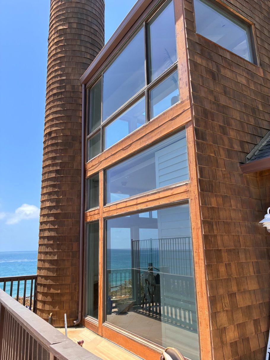 SBG: Dual Glaze Insulated Glass Units Modern seaside house with large windows and a wooden exterior near the ocean.